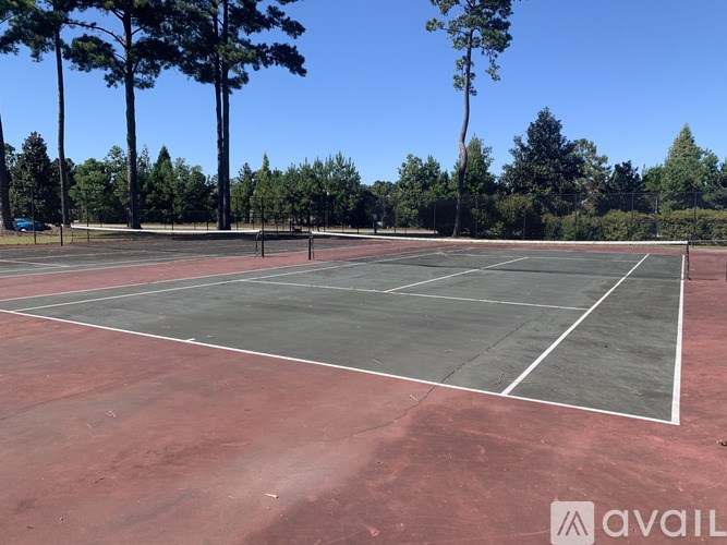 A tennis court with a net in the middle surrounded by trees.