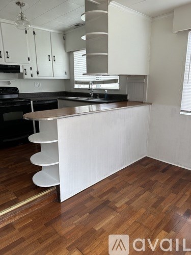 A kitchen with a white counter and wooden floors.