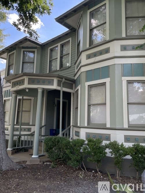 A two-story house with a front porch and a tree in front.