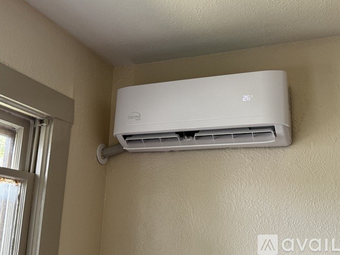 A white air conditioner is mounted on a beige wall.