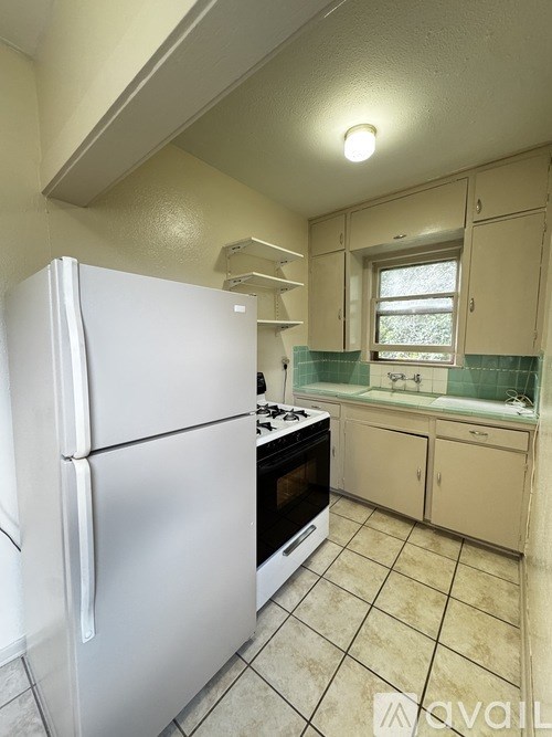 A white refrigerator is in a kitchen with beige cabinets.