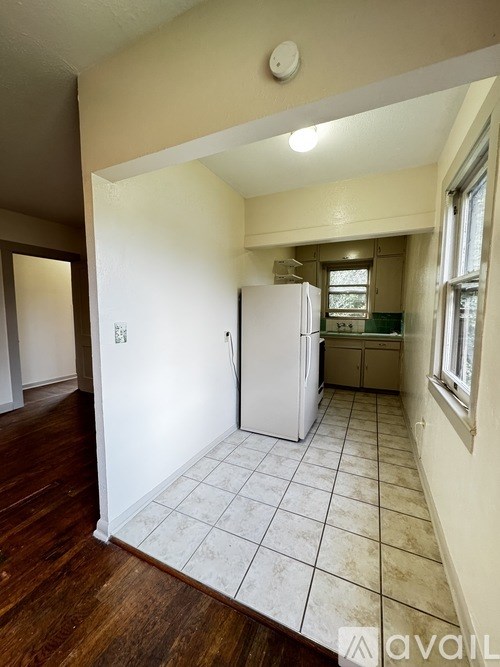 A kitchen with a white fridge and tiled floor.