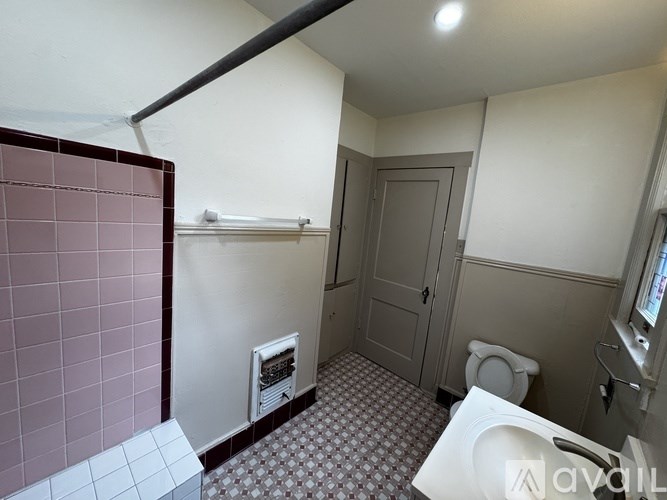 A bathroom with a toilet, sink, and a pink tiled wall.