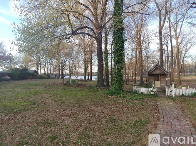 A small house with a white picket fence is surrounded by trees.