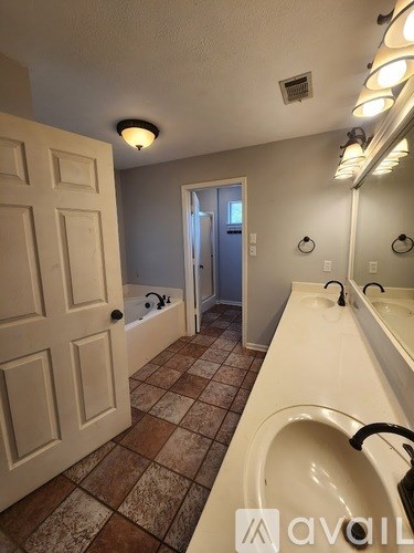 A bathroom with a white sink and brown tiles.