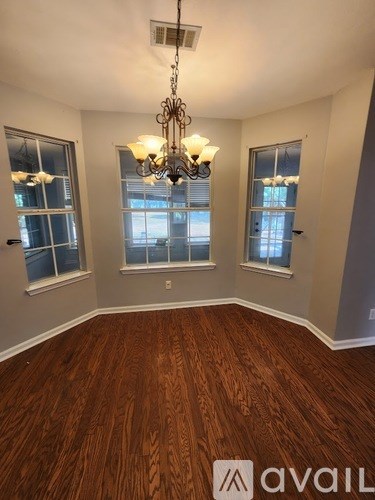 A room with wooden floors and a chandelier hanging from the ceiling.