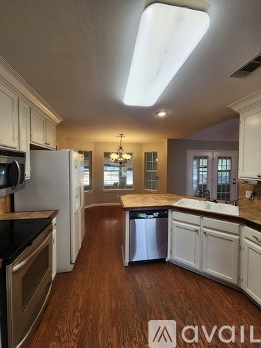A kitchen with white cabinets and a wooden floor.