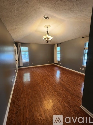 A room with wooden flooring and a chandelier.