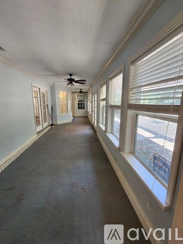 A long hallway with a fan and windows on both sides.