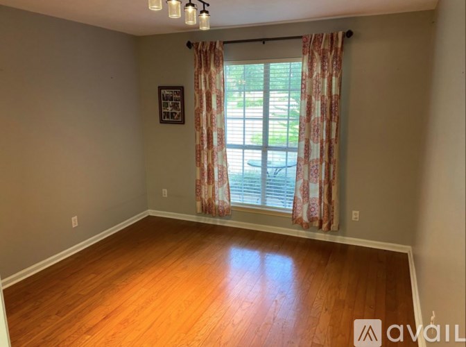 A room with wooden floors and a window with curtains.