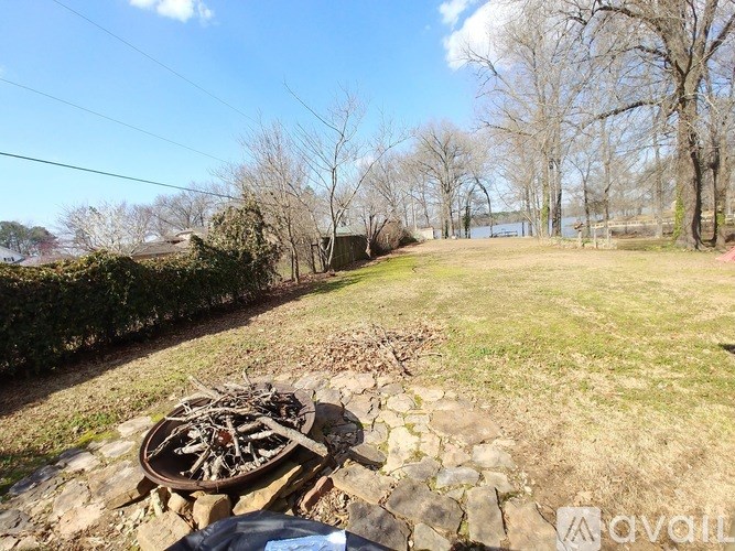 A fire pit with wood in it sits on a stone wall.