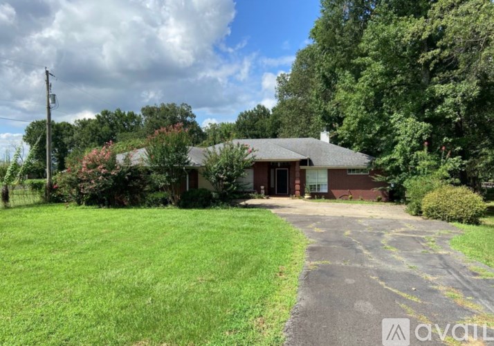 A house with a driveway in front of it surrounded by greenery.