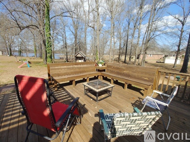 A wooden deck with chairs and a table is surrounded by trees.