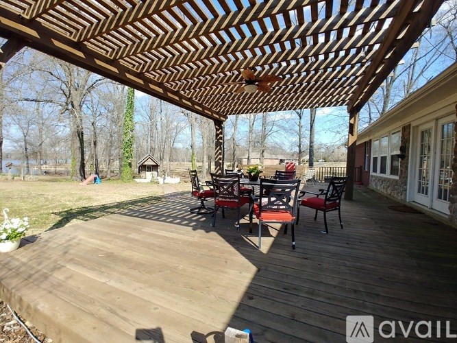 A wooden deck with chairs and a table under a pergola.