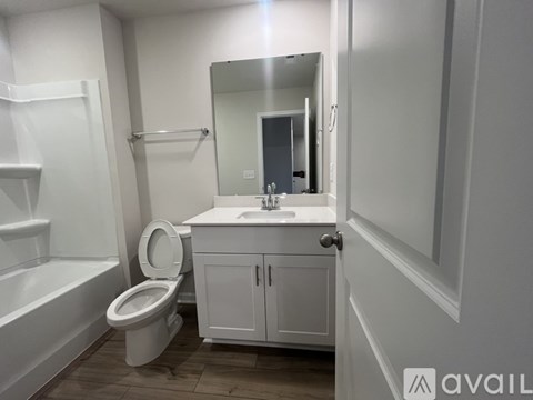 A white bathroom with a toilet, sink, and mirror.