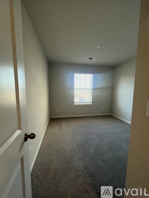 A room with a carpeted floor and a door on the left.
