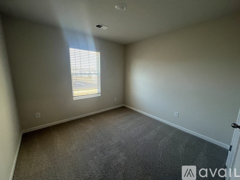 A room with a carpeted floor and a window with blinds.