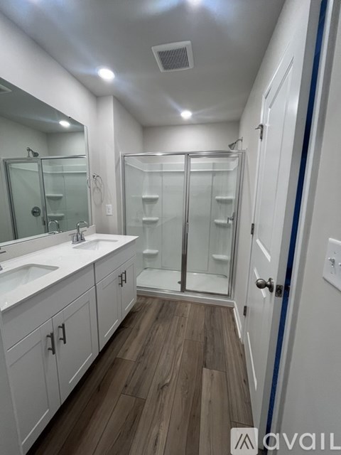 A bathroom with a white sink, mirror, and wooden floor.