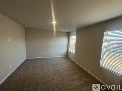 A spacious room with a carpeted floor and a window with blinds.