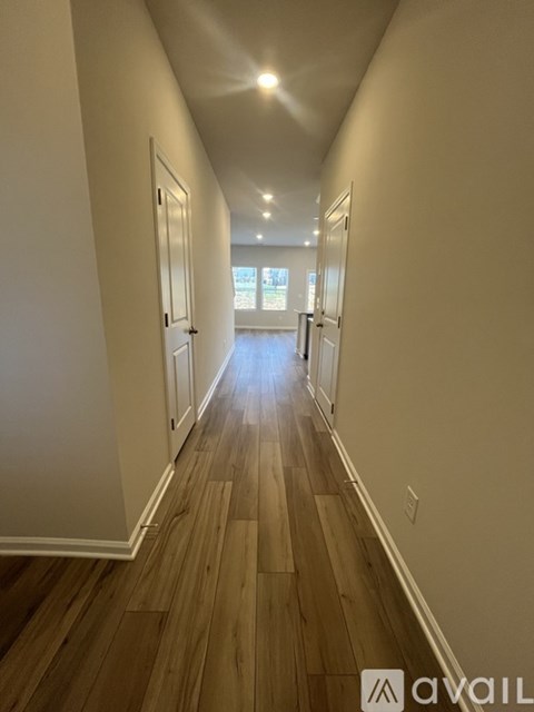 A long hallway with wood floors and white walls.