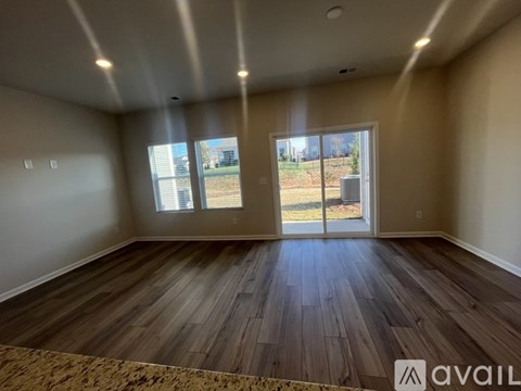 A room with wooden flooring and a sliding glass door leading to a backyard.