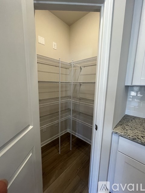 A white pantry with a door open to a kitchen.
