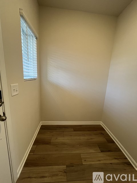 A room with wooden flooring and a window with blinds.