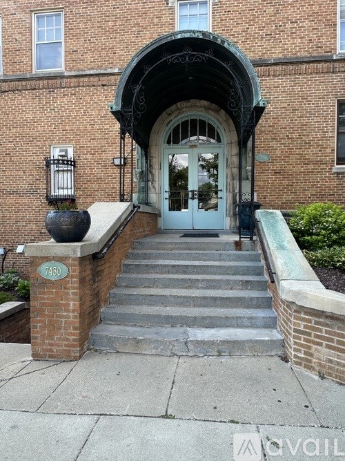 A brick building with a white door and a green staircase.