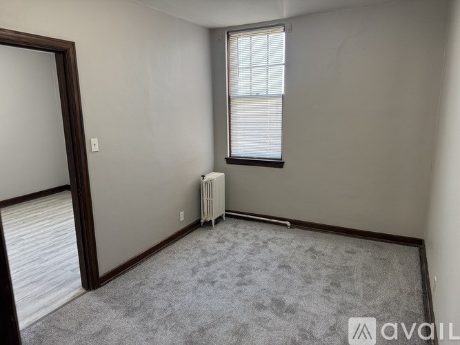 A room with a window and a radiator on the floor.