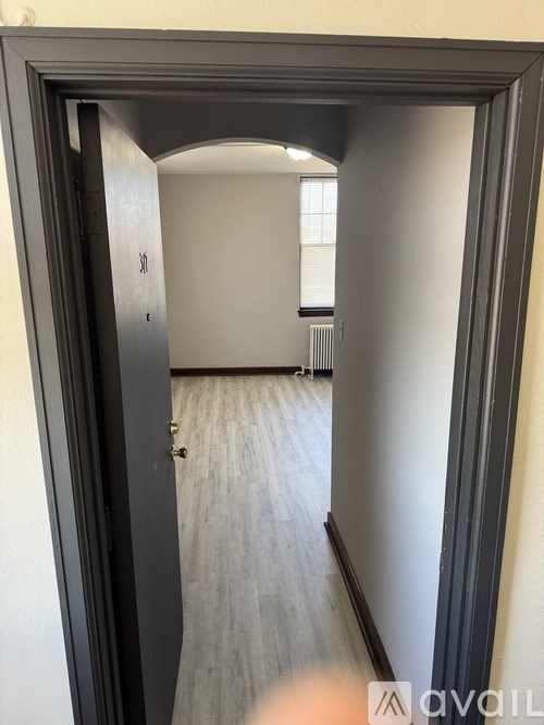 A hallway with a door on the left and a window on the right.