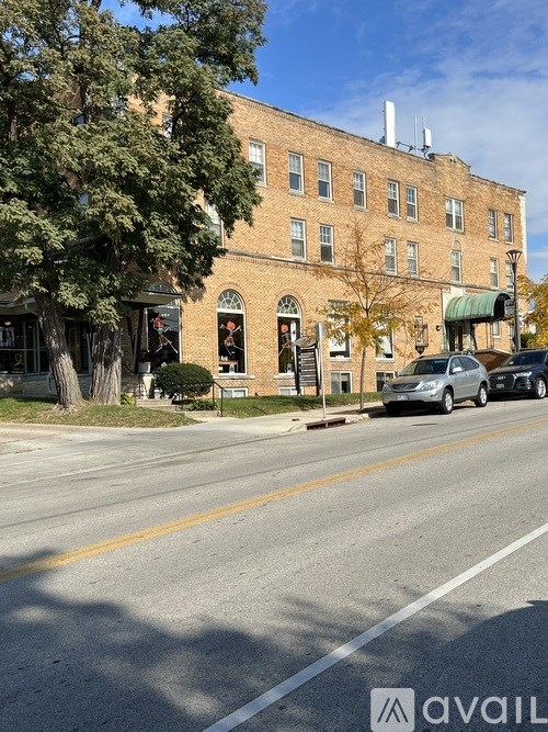 A street view with a building, cars and trees.