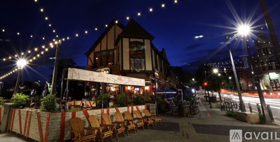 A restaurant with wooden chairs and tables is lit up at night.