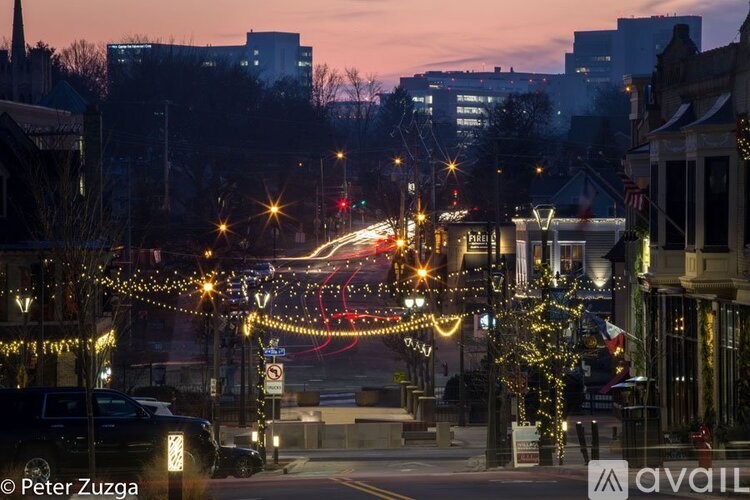 A city street at dusk with cars and buildings on either side.