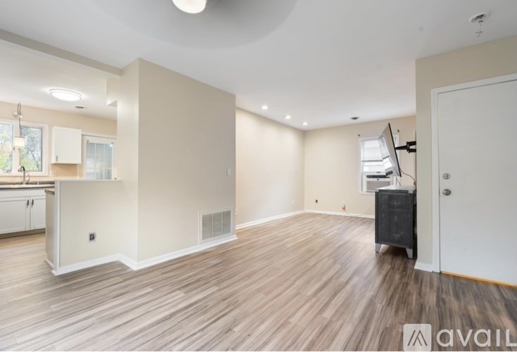 A room with wooden flooring and a kitchen area to the left.