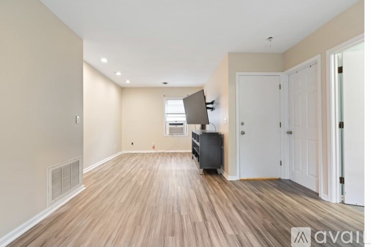 A room with wooden flooring and a flat screen TV mounted on the wall.