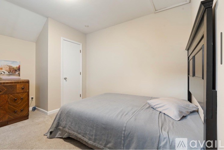 A bedroom with a bed, dresser, and painting on the wall.
