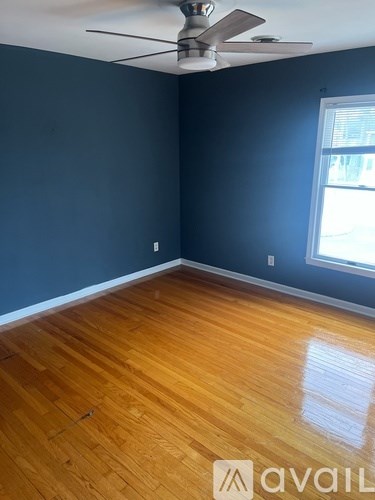 A room with a ceiling fan and wooden flooring.