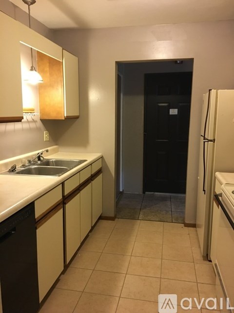 A kitchen with white cabinets and a black fridge.