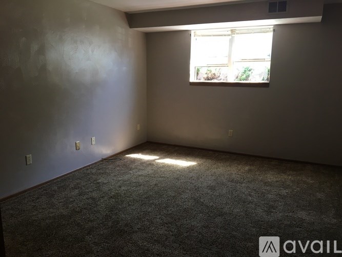 A room with a window and a carpeted floor.