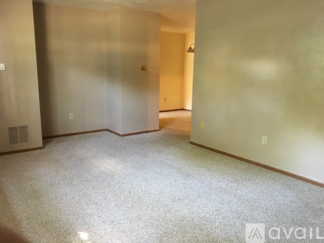 A spacious room with a carpeted floor and a door at the end.