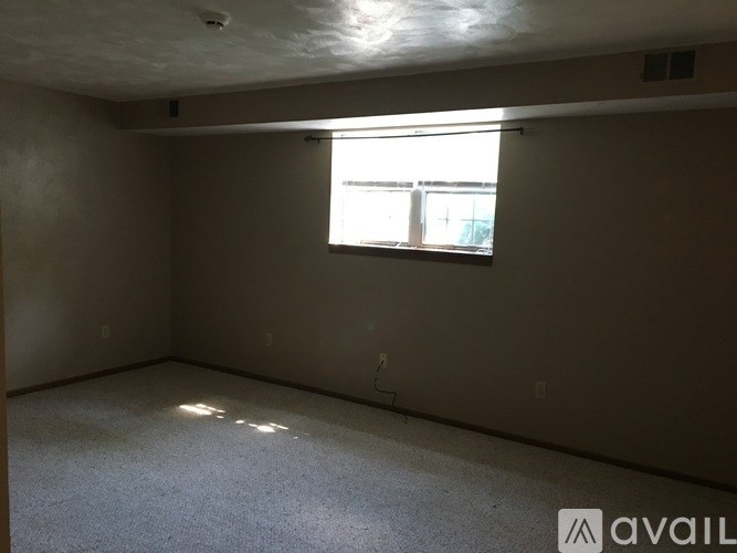 Empty room with a window and a carpeted floor.