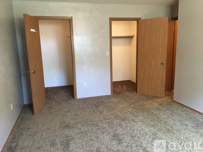Three wooden doors in a room with carpeted floor.