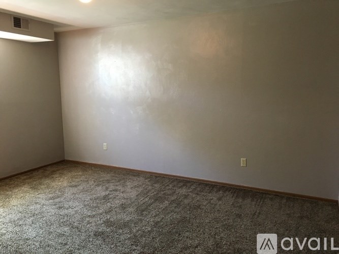 A room with a carpeted floor and a wall with a light switch.