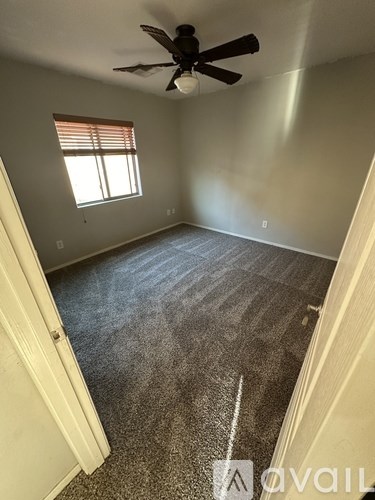 A room with a ceiling fan and a window with blinds.