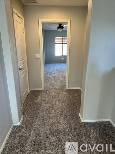 A hallway with a carpeted floor and a door at the end.