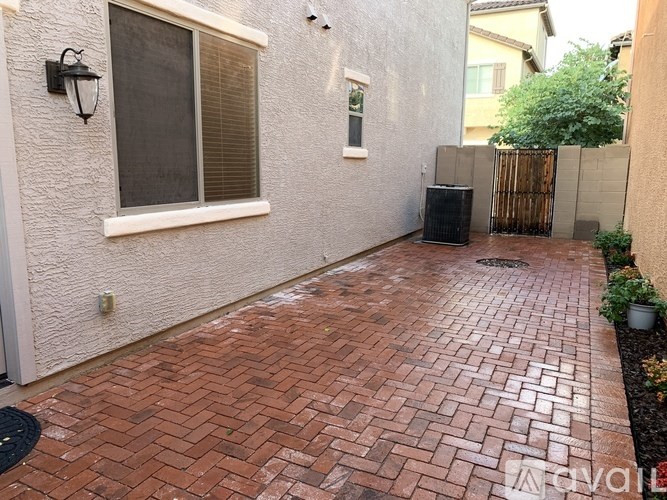 A patio with a brick pattern is in front of a house.