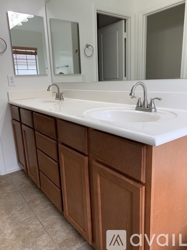 A bathroom vanity with two sinks and a mirror above it.