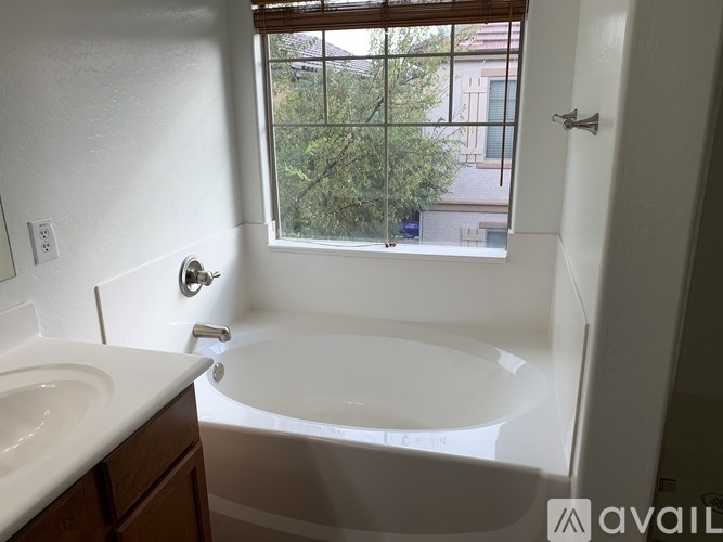 A white bathroom with a window overlooking a tree.