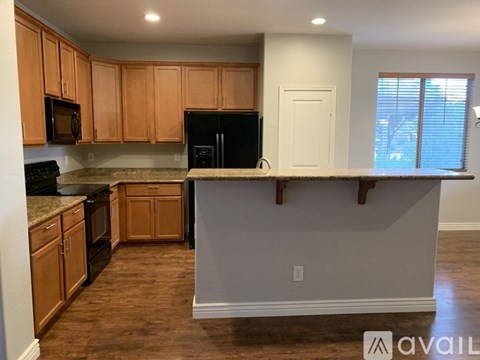 A kitchen with wooden cabinets and a black refrigerator.