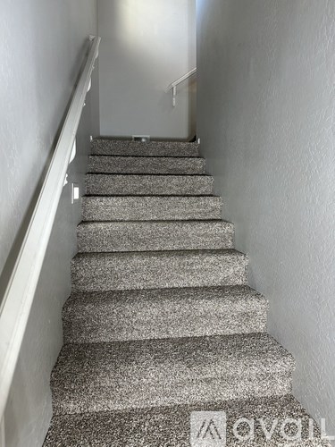 A staircase with grey carpeted steps and white railings.